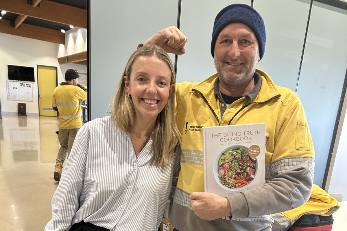 A dietitian sharing a laugh with a team member while holding The Biting Truth cookbook