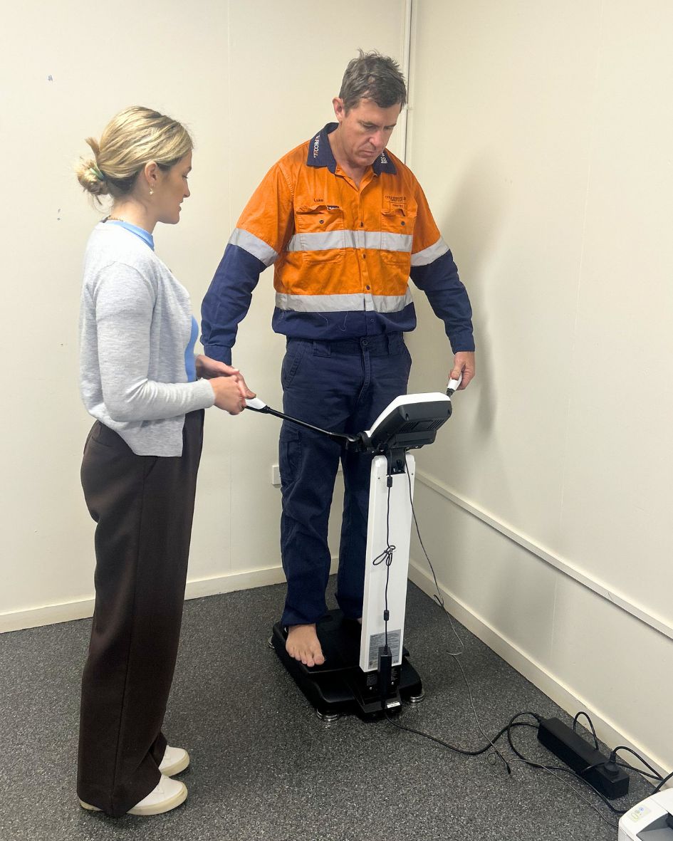 A dietitian running an InBody body composition scan with a team member on site