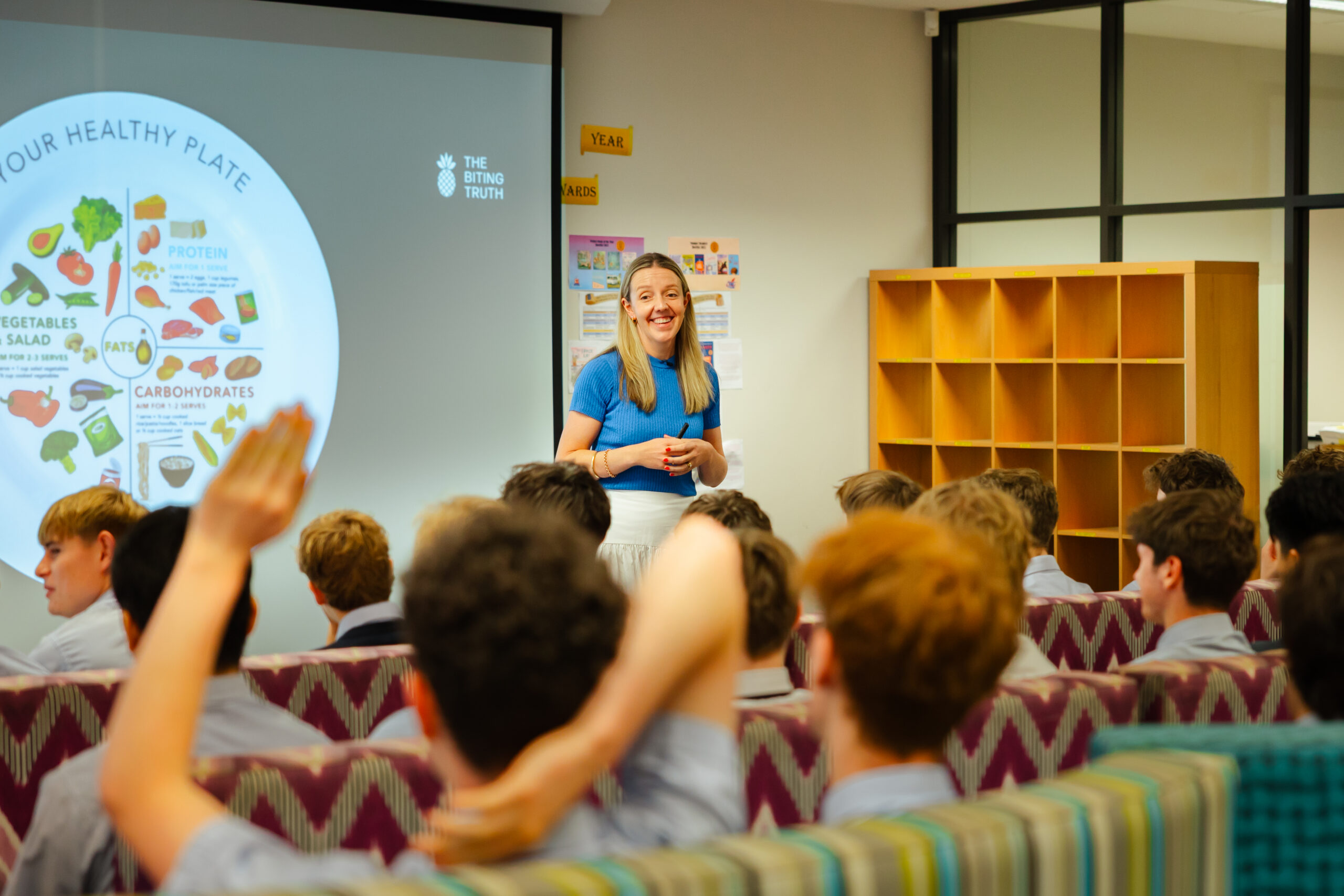 A Biting Truth dietitian presenting to a class of students with hands raised